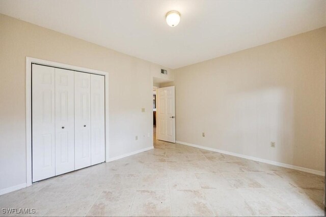 6025 Chardonnay Ln Unit 103, Naples, FL 34119 - unfurnished bedroom featuring light tile patterned floors, baseboards, visible vents, and a closet