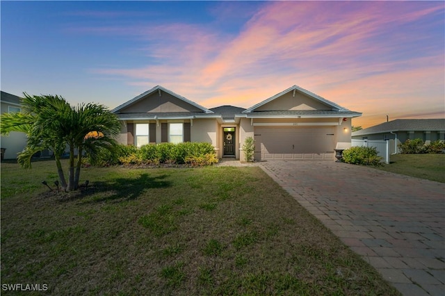 ranch-style home with a yard, a garage, decorative driveway, and stucco siding