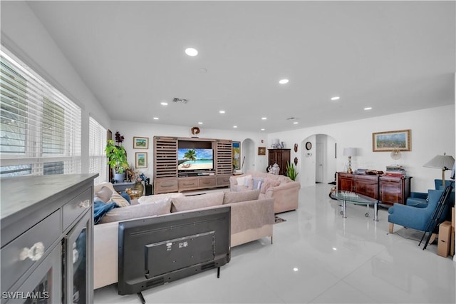 tiled living room with visible vents, recessed lighting, and arched walkways