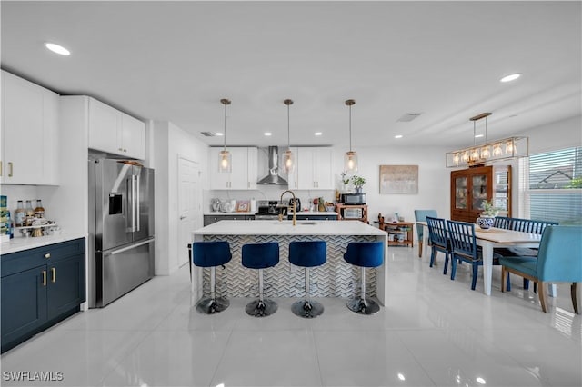 kitchen featuring light countertops, wall chimney range hood, high end fridge, and a kitchen breakfast bar
