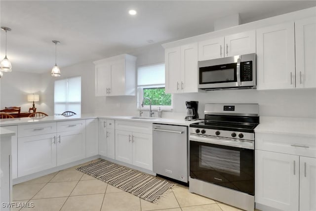 590 104th Ave N, Naples, FL 34108 - kitchen with stainless steel appliances, light countertops, a peninsula, white cabinets, and hanging light fixtures