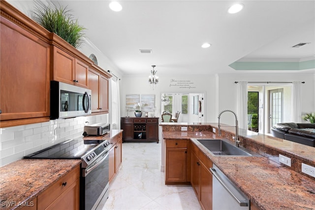 13599 Troia Dr, Estero, FL 33928 - kitchen featuring stainless steel appliances, a sink, brown cabinets, ornamental molding, and light stone counters