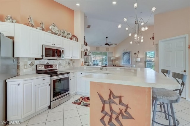 kitchen featuring appliances with stainless steel finishes, high vaulted ceiling, a kitchen breakfast bar, tasteful backsplash, and plenty of natural light