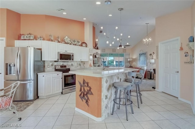 kitchen featuring stainless steel appliances, high vaulted ceiling, a chandelier, light countertops, and light tile patterned floors