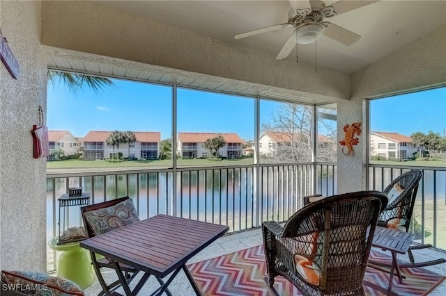 sunroom featuring a residential view, ceiling fan, and a water view