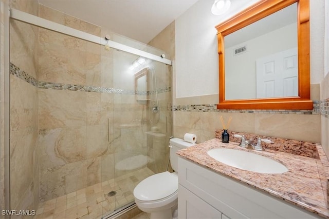 full bathroom with vanity, a shower stall, toilet, and visible vents