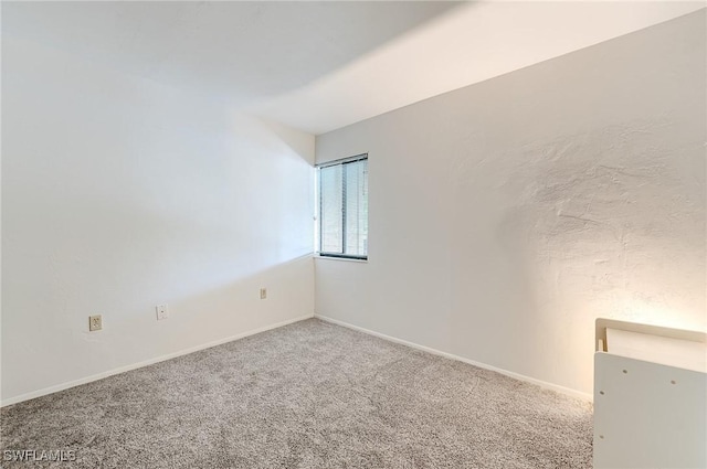 spare room with baseboards and carpet