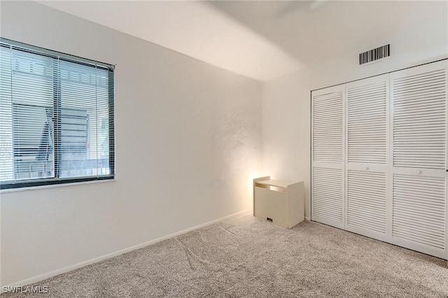 unfurnished bedroom featuring carpet floors, baseboards, a closet, and visible vents
