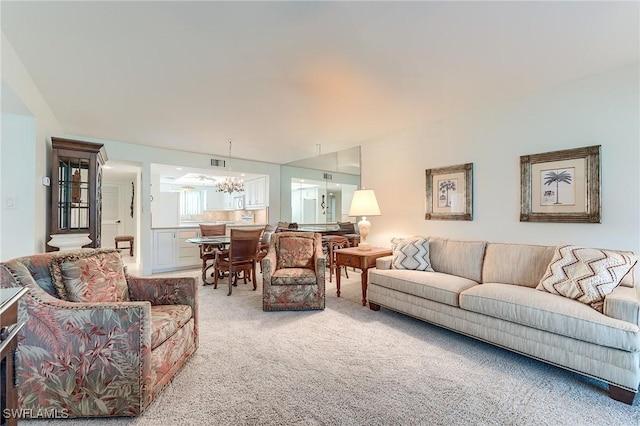 living area with an inviting chandelier, visible vents, and light carpet
