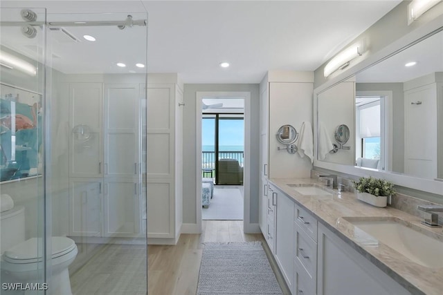 full bathroom featuring double vanity, a sink, toilet, and wood finished floors