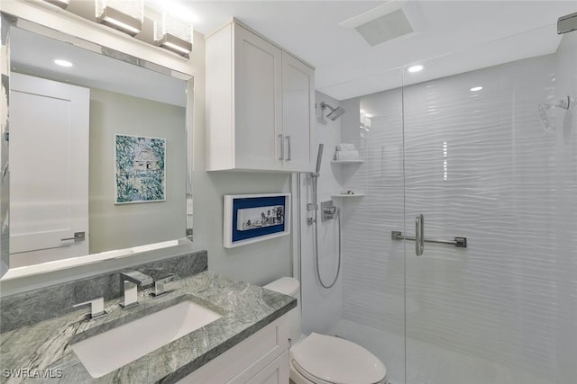 bathroom featuring vanity, visible vents, toilet, and a shower stall