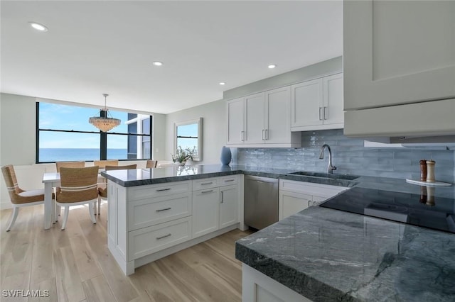 kitchen featuring white cabinetry, tasteful backsplash, a sink, dishwasher, and a peninsula