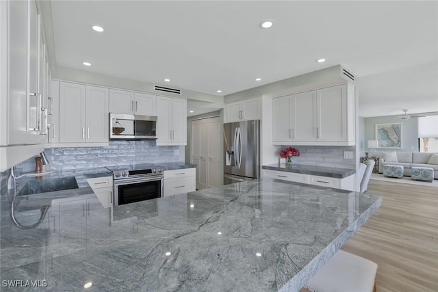 kitchen with visible vents, white cabinets, stone countertops, and appliances with stainless steel finishes