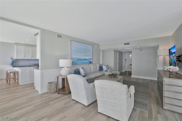 living room featuring light wood-style flooring and visible vents