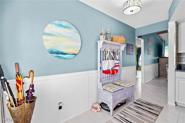 corridor featuring wainscoting and light tile patterned floors
