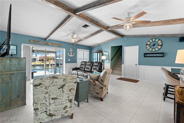 living area featuring a wainscoted wall, stairway, and a ceiling fan