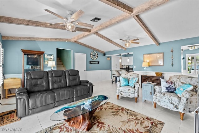 living room featuring lofted ceiling with beams, a wainscoted wall, visible vents, and a ceiling fan