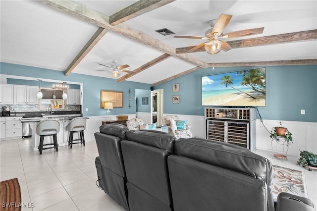 living room featuring a ceiling fan, a wainscoted wall, light tile patterned floors, and visible vents