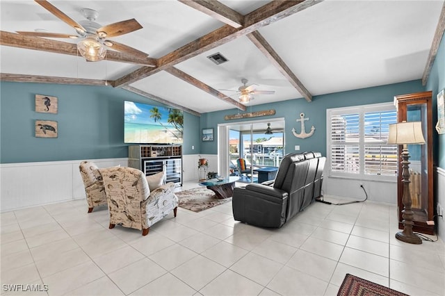 living area with a wainscoted wall, ceiling fan, visible vents, and plenty of natural light