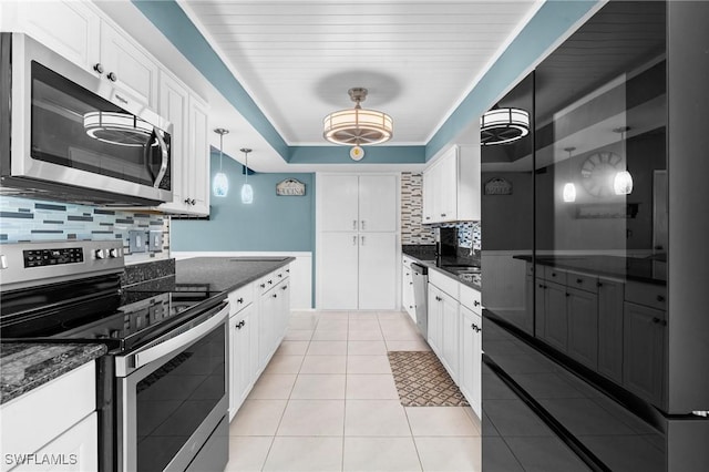kitchen featuring white cabinets, tasteful backsplash, light tile patterned floors, and stainless steel appliances