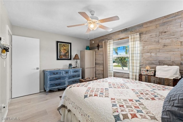 bedroom with wood walls, a ceiling fan, and wood finished floors