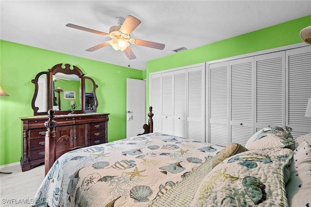 bedroom with baseboards, multiple closets, visible vents, and ceiling fan