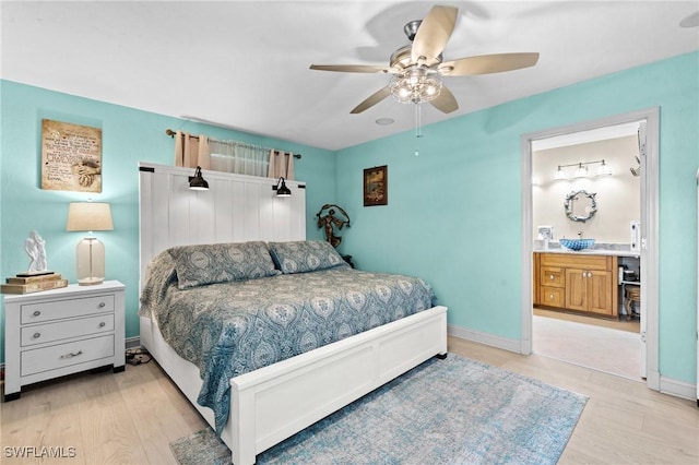 bedroom with baseboards, light wood-style floors, ceiling fan, and ensuite bath