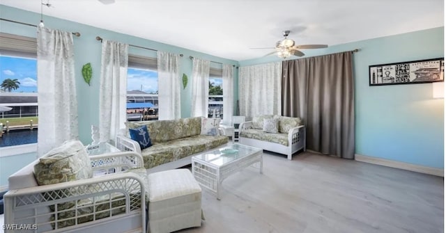 living room featuring baseboards, wood finished floors, and a ceiling fan