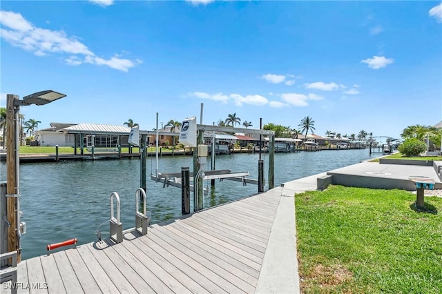 dock area featuring a water view, boat lift, and a yard