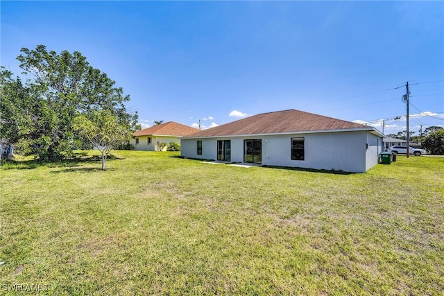 rear view of property with stucco siding and a yard
