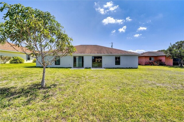 rear view of property with a lawn and stucco siding