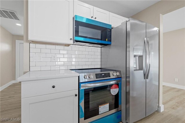 1725 SE 3rd St, Cape Coral, FL 33990 - kitchen featuring tasteful backsplash, visible vents, white cabinets, light wood-style floors, and stainless steel appliances