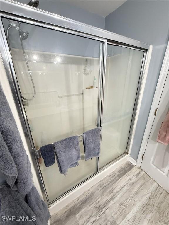 full bath featuring wood finished floors and a shower stall