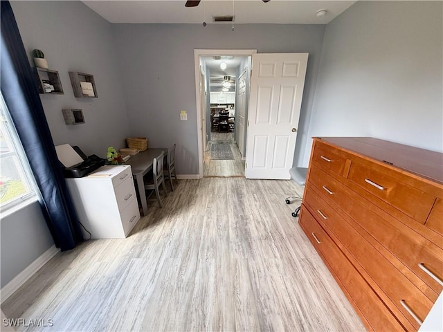 unfurnished office with baseboards, visible vents, a ceiling fan, and light wood finished floors