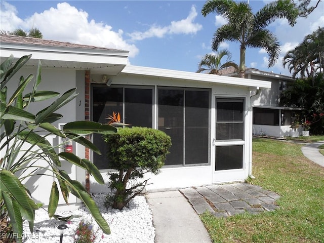 entrance to property with stucco siding and a yard