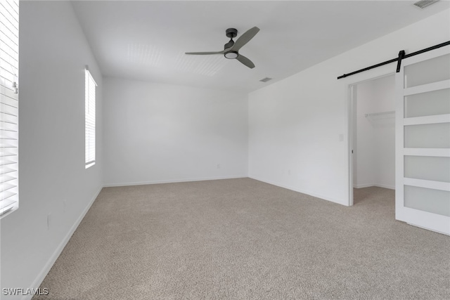 26974 Wildwood Pines Ln, Bonita Springs, FL 34135 - unfurnished bedroom with a barn door, carpet flooring, a spacious closet, and ceiling fan