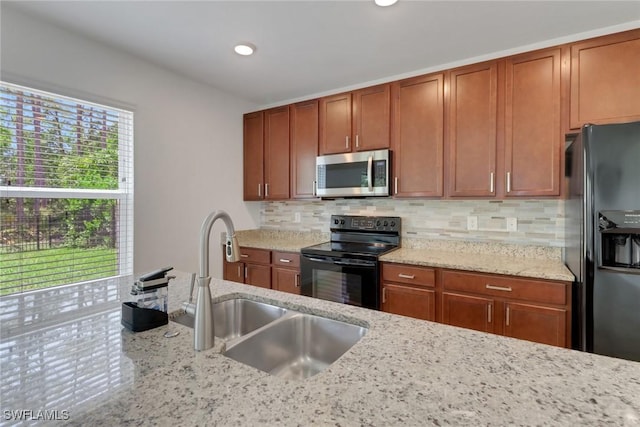 26974 Wildwood Pines Ln, Bonita Springs, FL 34135 - kitchen featuring black appliances, a sink, light stone countertops, decorative backsplash, and brown cabinets