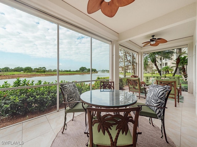sunroom featuring a ceiling fan, a water view, and tile patterned floors