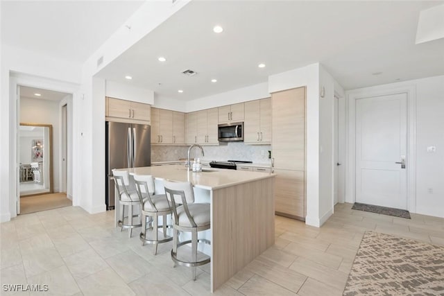 1111 Central Ave Unit 507, Naples, FL 34102 - kitchen with stainless steel appliances, a breakfast bar, a sink, light countertops, and decorative backsplash