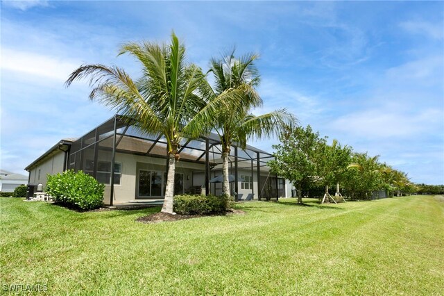 back of property featuring a lawn, stucco siding, and a lanai