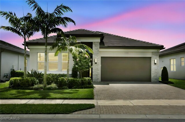 ranch-style home with stucco siding, a tile roof, decorative driveway, and an attached garage