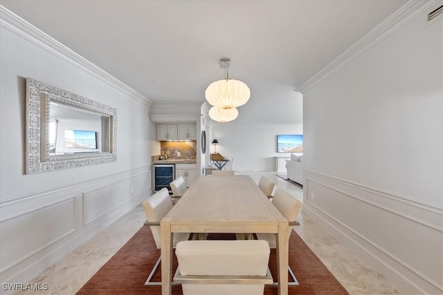 174 S Collier Blvd Unit 504, Marco Island, FL 34145 - dining area featuring crown molding, wine cooler, plenty of natural light, a decorative wall, and wainscoting