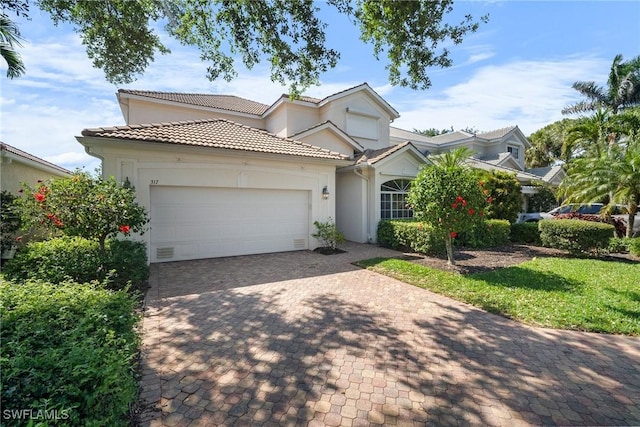 view of front of home featuring a tiled roof, an attached garage, driveway, and stucco siding