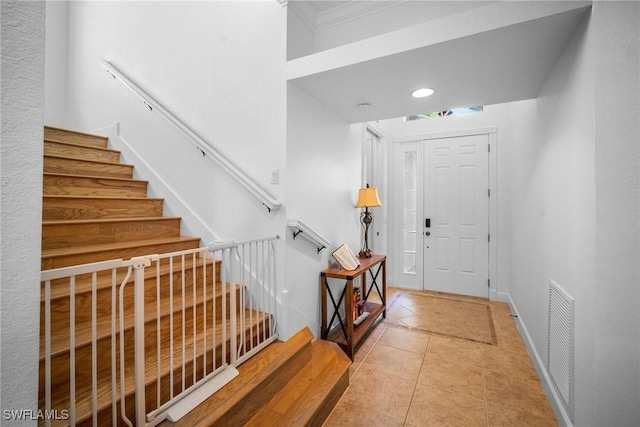 entrance foyer featuring baseboards, stairway, light tile patterned floors, crown molding, and visible vents