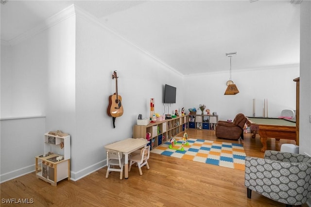 playroom with wood finished floors, baseboards, and ornamental molding