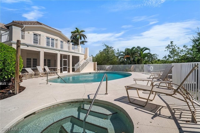 pool featuring fence, a patio area, stairway, and a community hot tub