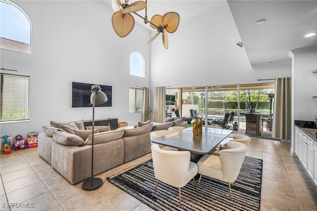 living room featuring light tile patterned floors, a ceiling fan, a high ceiling, and a healthy amount of sunlight