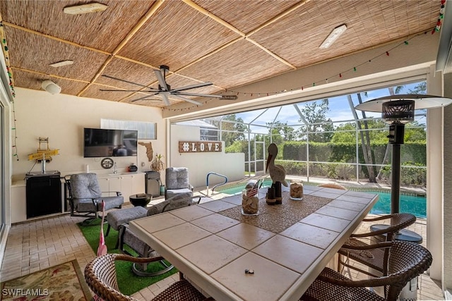sunroom / solarium featuring outdoor dining space and a ceiling fan
