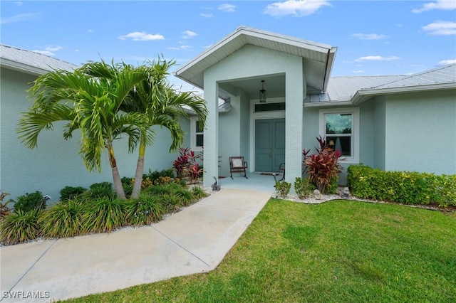 14190 Binghampton Dr, Fort Myers, FL 33905 - property entrance featuring stucco siding, a lawn, and a metal roof