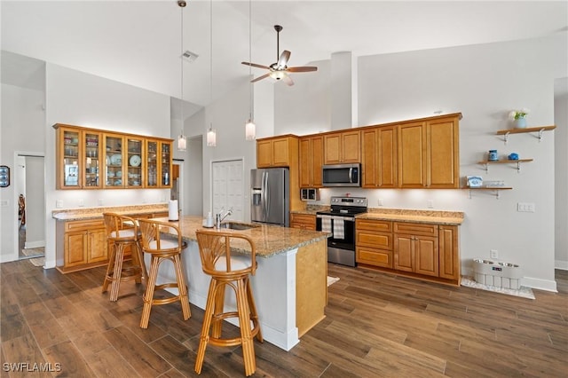 14190 Binghampton Dr, Fort Myers, FL 33905 - kitchen with stainless steel appliances, a towering ceiling, brown cabinets, dark wood-style flooring, and a ceiling fan